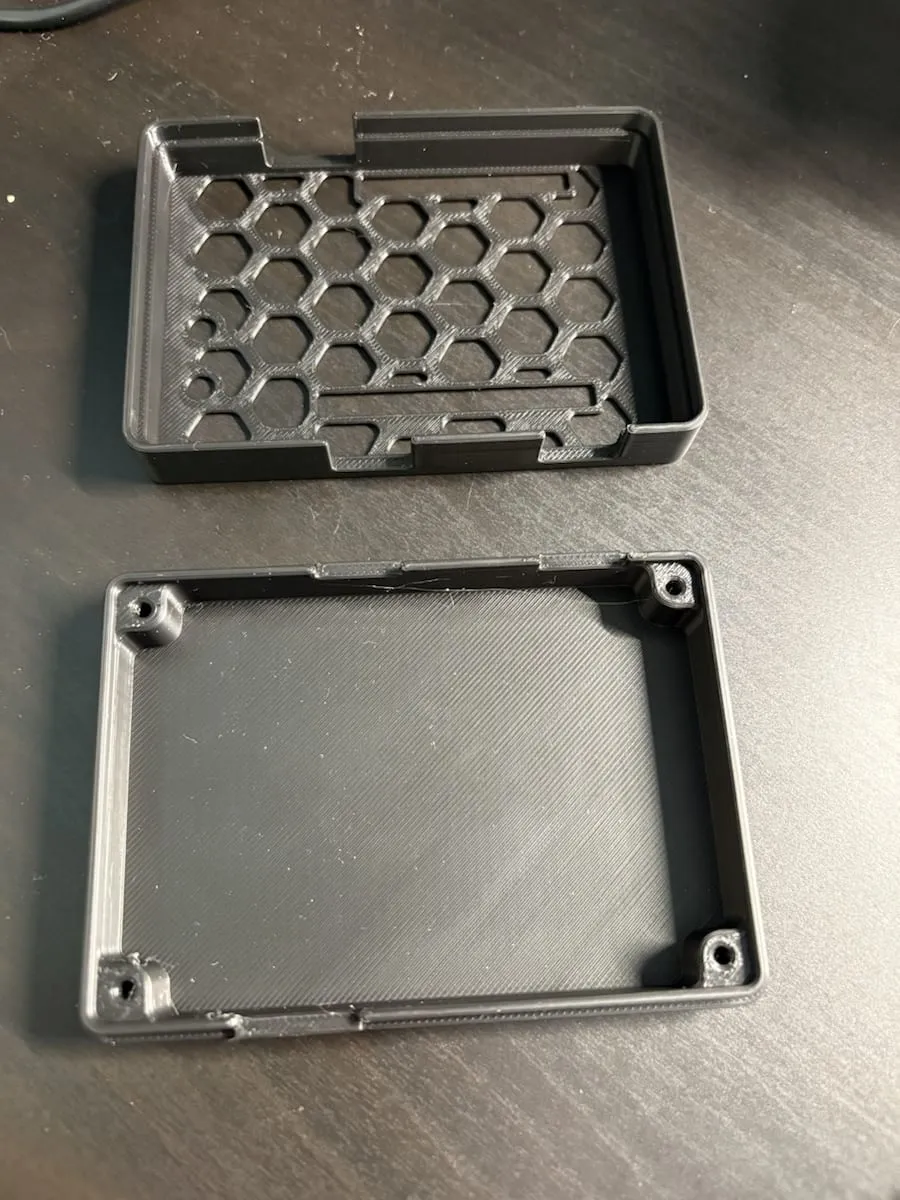Two-piece 3D printed enclosure showing the vented top shell and the base with simple mounting posts